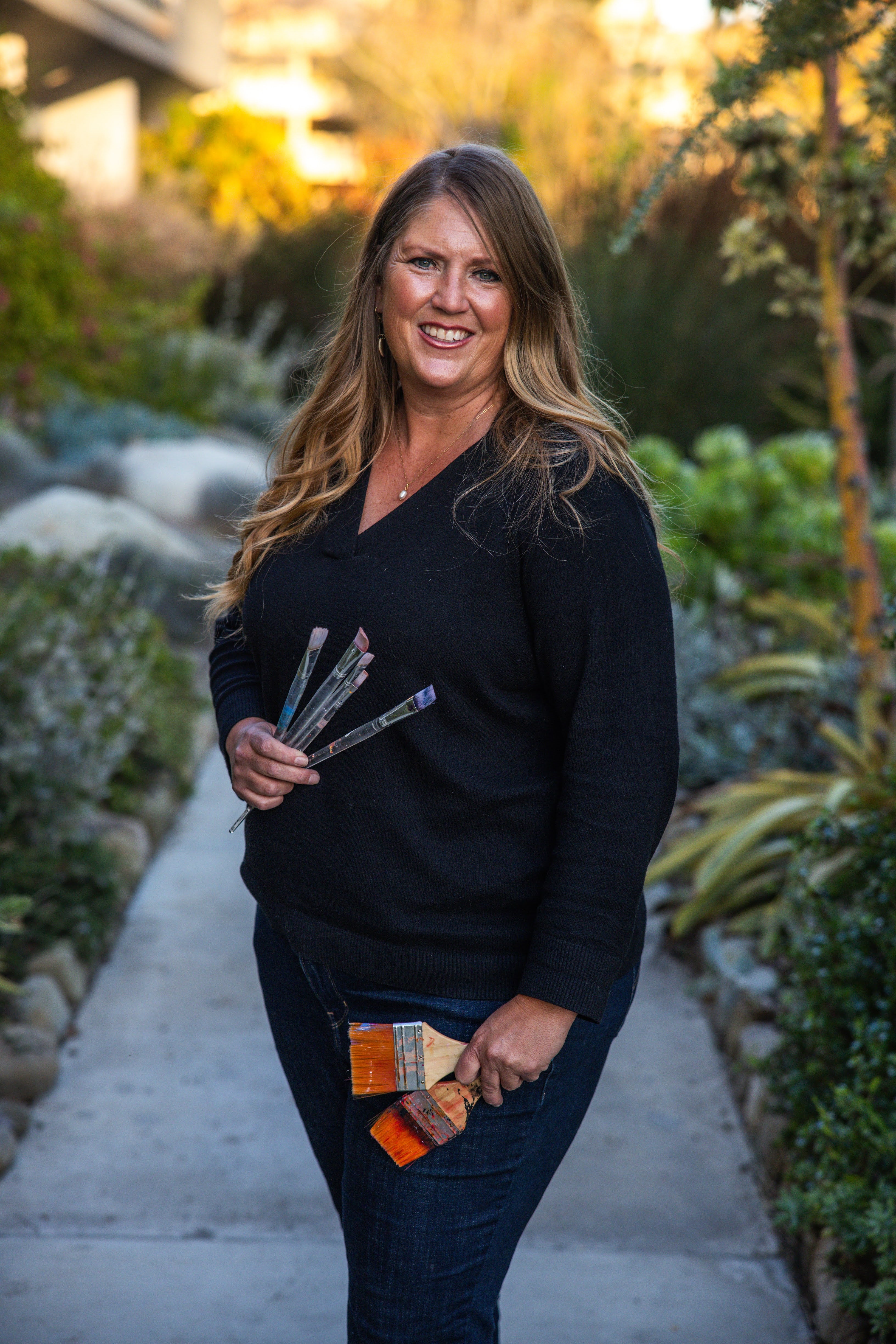 Jamie Wells painting in her studio, creating original artwork with vibrant colors and expressive brushstrokes.